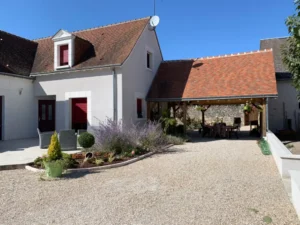 Maison avec volets rouges et cour gravillonnée