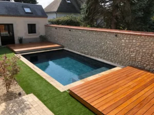 Piscine moderne avec terrasse en bois et mur en pierre