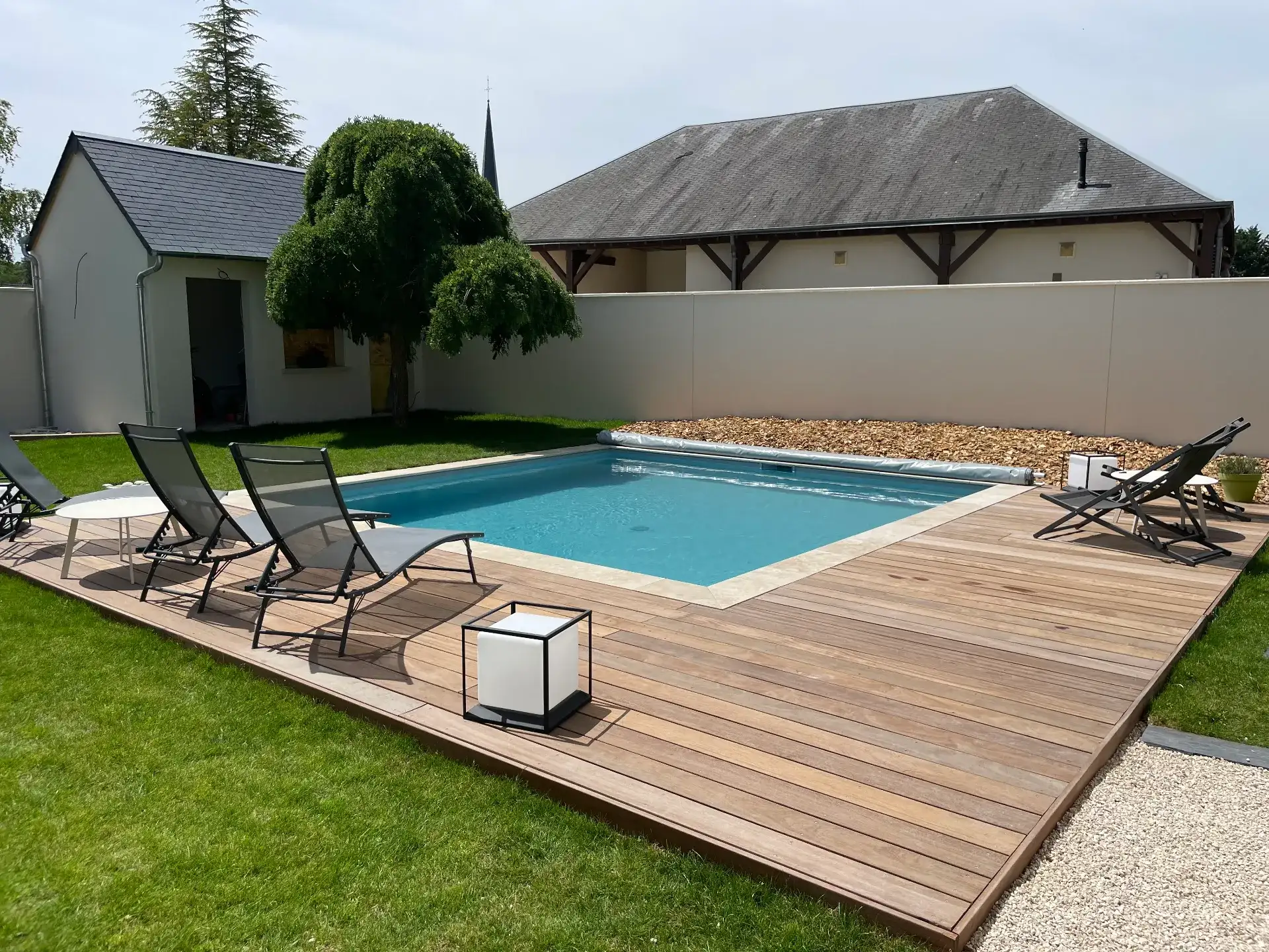 Piscine moderne avec terrasse en bois et transats