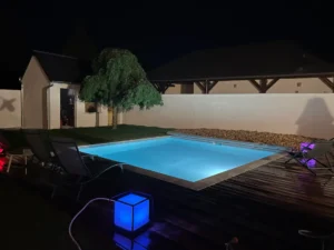 Piscine illuminée dans jardin moderne la nuit