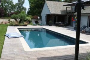 Piscine moderne avec terrasse en bois et jardin