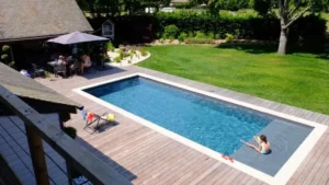 Piscine rectangulaire dans jardin avec terrasse en bois