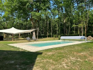 Piscine extérieure dans jardin boisé avec voile d’ombrage