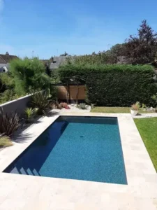 Piscine rectangulaire moderne dans jardin paysager ensoleillé