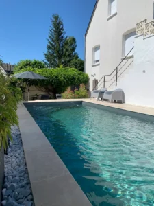 Piscine moderne dans jardin avec maison blanche