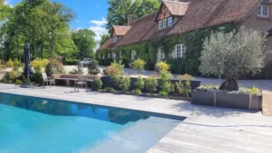 Piscine moderne devant maison en pierre végétalisée