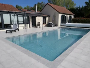 Piscine moderne devant maison avec terrasse carrelée