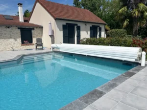Piscine extérieure moderne devant maison avec volets bleus