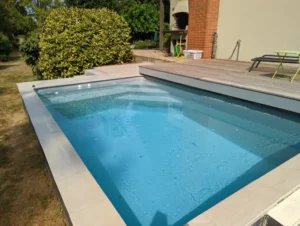 Petite piscine rectangulaire dans jardin avec terrasse bois