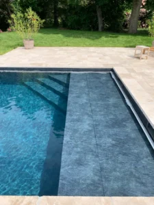 Piscine moderne avec plage immergée et terrasse en pierre