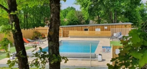 Piscine extérieure entourée d’arbres et clôture en bois