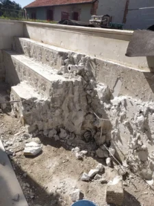 Escaliers en béton endommagés avec gravats et canalisation
