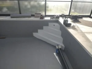 Piscine intérieure en rénovation avec escalier blanc