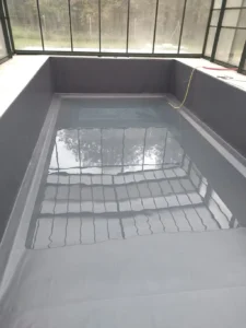 Petite piscine intérieure rectangulaire partiellement remplie d’eau