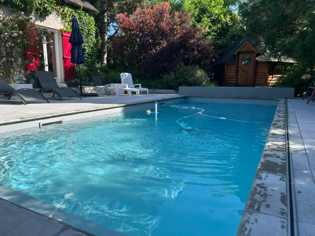 Piscine extérieure avec transats et jardin verdoyant