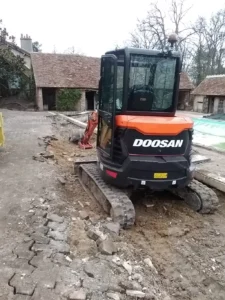 Mini-pelle Doosan creusant une allée pavée